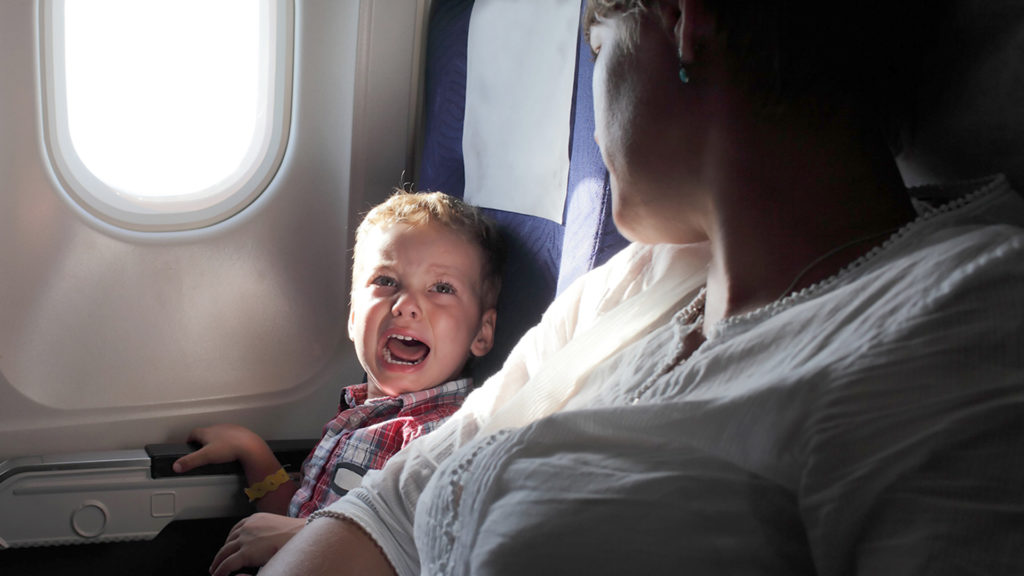 A crying toddler with parent on airplane